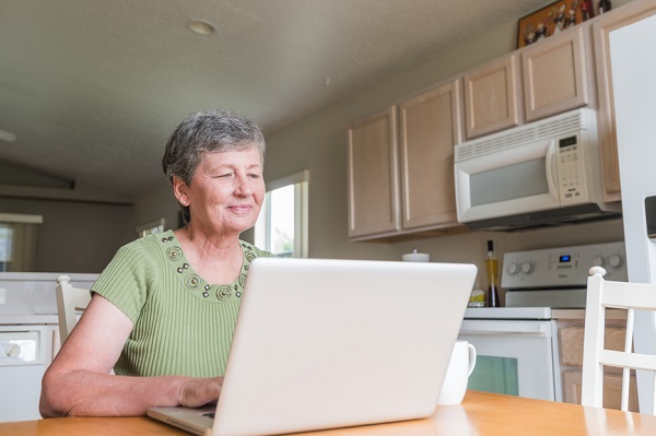 Senior citizen using laptop in the kitchen