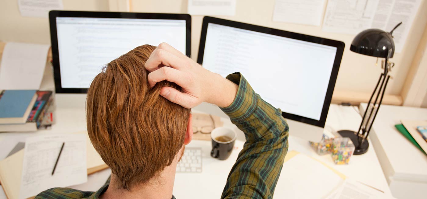A man scratching his head in frustration due to computer problems